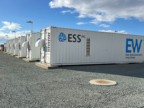 Six ESS Energy Warehouse battery energy storage system containers lined up at a PXiSE project site.