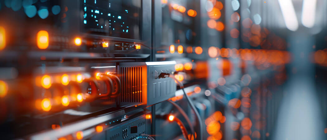 Blurry led lights shine orange on a bank of energy generation monitoring and switchgear equipment.